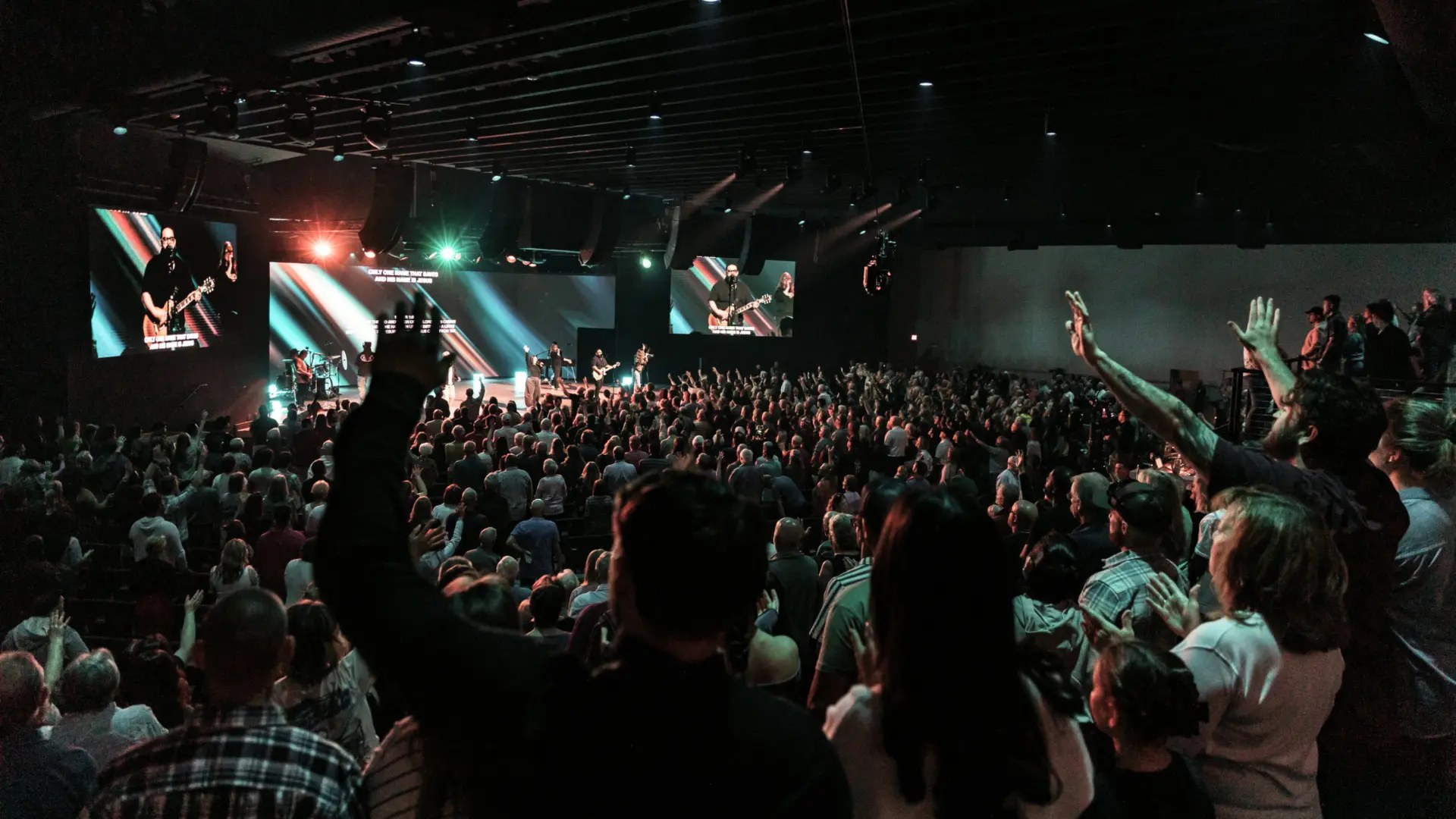 A packed church auditorium with hands raised during worship