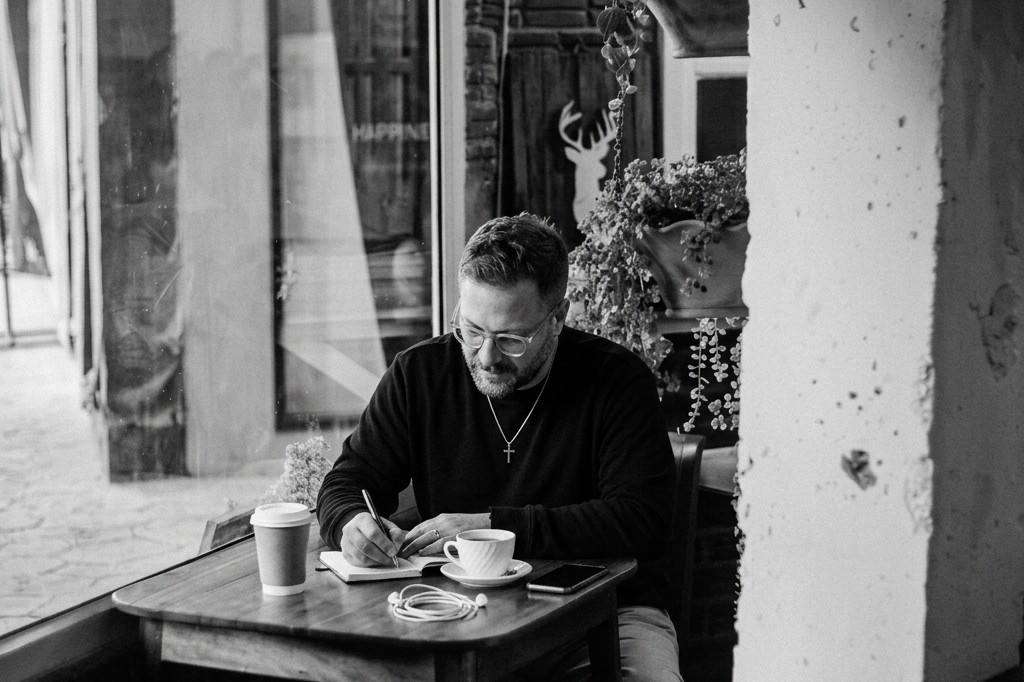 Jesse LaBauve, founder of Ugly Monk, writing in a notebook at a coffee shop